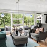 Wohnzimmer mit Sofa, Sesseln und großem Fenster. Holzboden und helle Wände.