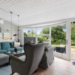 Wohnzimmer mit Sofa, Sessel und Blick auf die Terrasse.