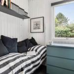Schlafzimmer mit Bett, Schrank und Fensterblick auf Grünflächen.