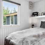 Schlafzimmer mit Bett, Fenster und Wandregal mit Dekoration.