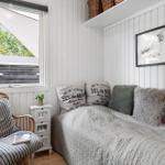 Schlafzimmer mit Bett, Stuhl und Fensterblick auf Holzhaus