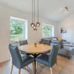 Essbereich mit runden Tisch und Stühlen. Wohnbereich mit Sofa und Fenstern.