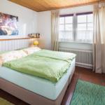 Schlafzimmer mit Doppelbett, Holzdecke, Fenster und Schrank.