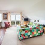 Wohnzimmer mit Sofa, TV und Balkonblick. Holzmöbel und Teppichboden.