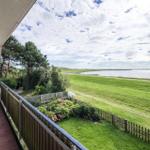 Terrasse mit Sitzgelegenheiten und Blick auf Grünfläche und Wasser.