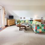 Wohnzimmer mit Sofa, Couchtisch und TV. Terrasse mit Blick nach draußen.