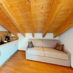 Wohnbereich mit Sofa, Küchenzeile und Holzdecke.