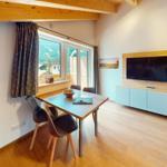 Essbereich mit Tisch, Stühlen und TV. Fenster mit Blick auf die Berge.