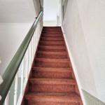 Staircase with red carpet and white balustrade leads upward.