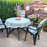 Round table with chairs, tablecloth, and plants in the garden.