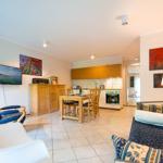 Wohnküche mit Esstisch, Sofa, TV und Küchenzeile.