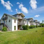 Modernes Mehrfamilienhaus mit Balkonen und Garten unter blauem Himmel.