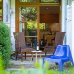 Terrasse mit zwei Stühlen und einem blauen Kunststoffstuhl. Im Hintergrund ist die Küche sichtbar.