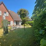 Rotes Backsteingebäude mit Garten und Sitzgelegenheit.