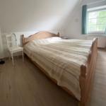 Schlafzimmer mit Doppelbett, Fenster und Holzboden.