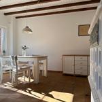 Esszimmer mit Tisch, Stühlen und Fenster. Holzbalken an der Decke.