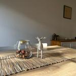 Esstisch mit Deko, Glas mit Nüssen und Hirschfigur auf Bambusläufer.