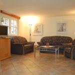 Wohnzimmer mit Sofa, Sesseln, Fernseher und Tisch.