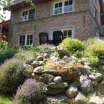Steinmauer mit Blumen und Sitzgelegenheit vor einem Backsteinhaus