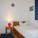 Ein Schlafzimmer mit Holzbett, Nachttisch und roter Lampe.