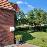 Rotes Backsteinhaus mit Garten, Blumenkasten und Satellitenschüssel.