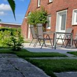 Roter Backsteinhaus mit Terrasse, Tisch und Stühlen im Garten.