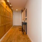 Flur mit Holzwand und Boden, Tisch und Wandregal.