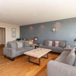 Wohnzimmer mit grauen Sofas, Holzboden und dekorativer Wand