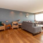 Wohnzimmer mit grauem Sofa, Holzboden und dekorativer Wand