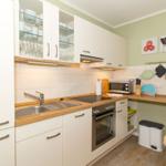 Küche mit weißen Schränken, Holz Arbeitsplatte und integriertem Herd.