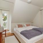 Schlafzimmer mit Doppelbett, Schreibtisch und Fenster zur Terrasse.