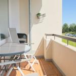 Terrasse mit Tisch und Stühlen, Blick auf Parkplatz und Grünfläche.