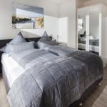 Schlafzimmer mit Doppelbett, Spiegelschrank und Wandbild.