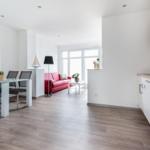 Wohnung mit Küche, Essbereich und Wohnzimmer mit rotem Sofa.