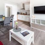 Wohnzimmer mit Essbereich und Küche. TV, Couch und Esstisch sind sichtbar.