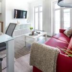 Wohn- und Essbereich mit rotem Sofa, Glas-Tisch und TV an der Wand.