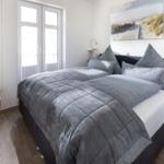 Schlafzimmer mit Doppelbett, Fenster und Wandbild.