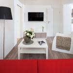 Wohnzimmer mit rotem Sofa, weißem Couchtisch und Fernseher an der Wand.