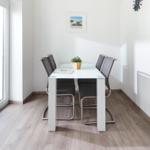 Essbereich mit Tisch und vier Stühlen, Glasplatte, Pflanze und Fenster.