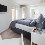 Schlafzimmer mit Bett, Nachttisch, Fernseher und Fenster.