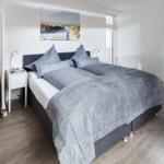 Schlafzimmer mit Doppelbett, Wandbild und TV. Holzstufen führen zu einer weiteren Ebene.