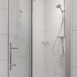 Duschkabine mit Glaswand, Duschbrause und Ablagekorb.