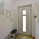 Eingangsbereich mit Tür, Spiegel, Schalter und Schlüsselhalter an der Wand.