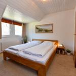 Schlafzimmer mit Doppelbett, Fenster und Holzbett.