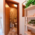 Badezimmer mit Toilette und Waschbecken. Holzdekor und Pflanzen.