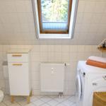 Badezimmer mit Waschmaschine, Toilette und Dachfenster.