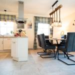 Küche und Essbereich mit Tisch, Stühlen und Plaidvorhängen.