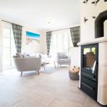 Wohnzimmer mit Kamin, Sitzgelegenheiten und Fenstern zum Ausblick.