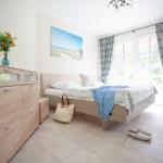 Schlafzimmer mit Bett, Schrank und Fenster mit Vorhängen.