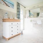 Badezimmer mit Waschbecken, Spiegel und Schrank. Fliesenwand und Boden.